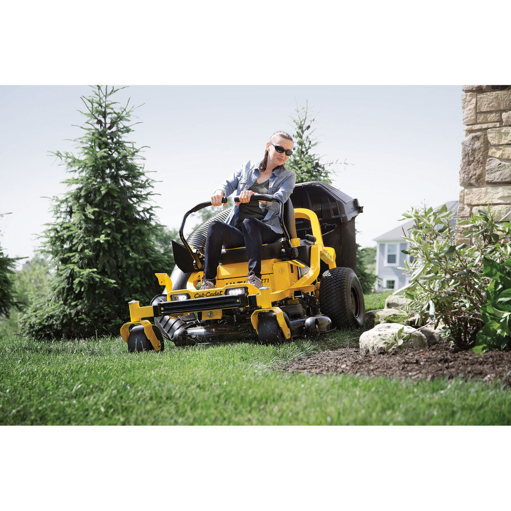 Person operating a yellow riding lawn mower in a garden setting