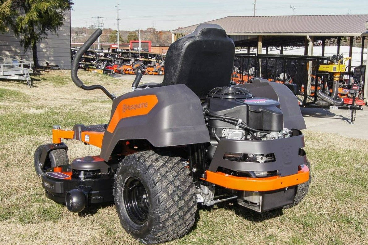 Lawn mower on display at an outdoor event with a building and trees in the background.