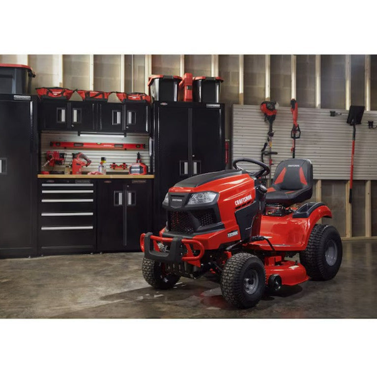 Red riding lawn mower in a workshop setting with tools and equipment.

