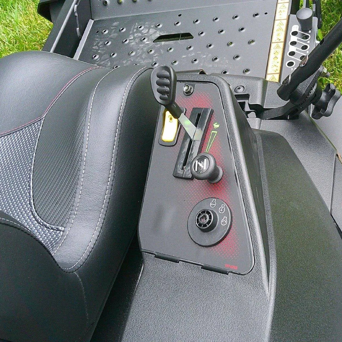 Close-up of a vehicle's control panel and seat with grass in the background

